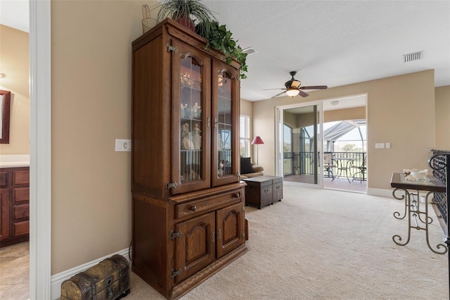 corridor with baseboards, visible vents, and light colored carpet
