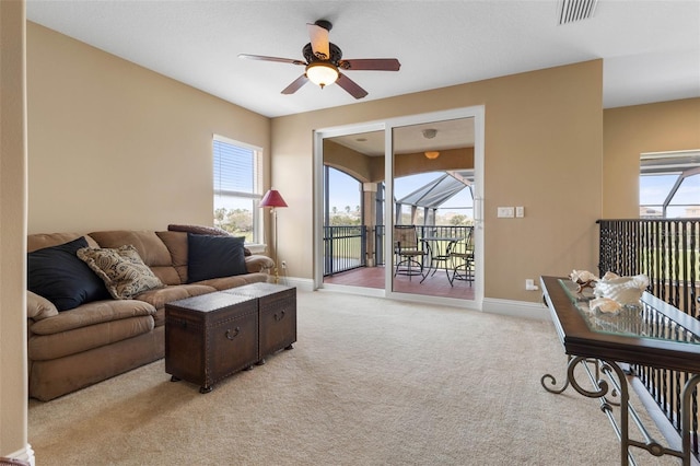 living room featuring light colored carpet, visible vents, ceiling fan, and a wealth of natural light