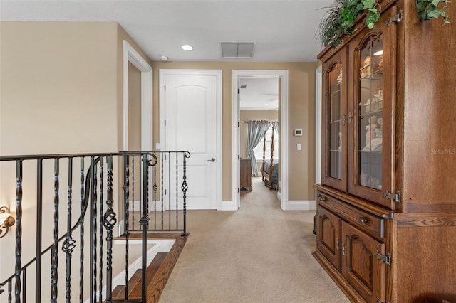 hallway with carpet floors, an upstairs landing, baseboards, and visible vents