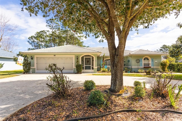 view of front of property with stucco siding, concrete driveway, an attached garage, and a tile roof