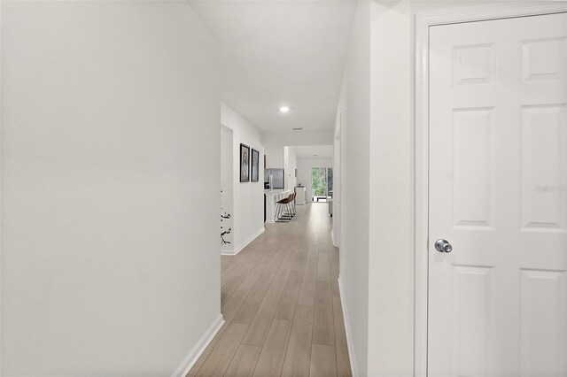 hall with light wood finished floors and baseboards