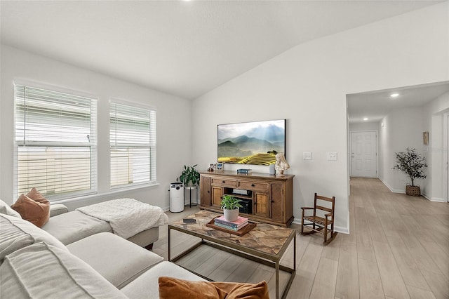 living room with light wood-style flooring, baseboards, and vaulted ceiling