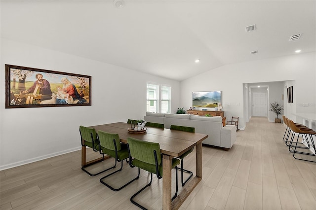 dining space featuring visible vents, vaulted ceiling, and light wood-style flooring