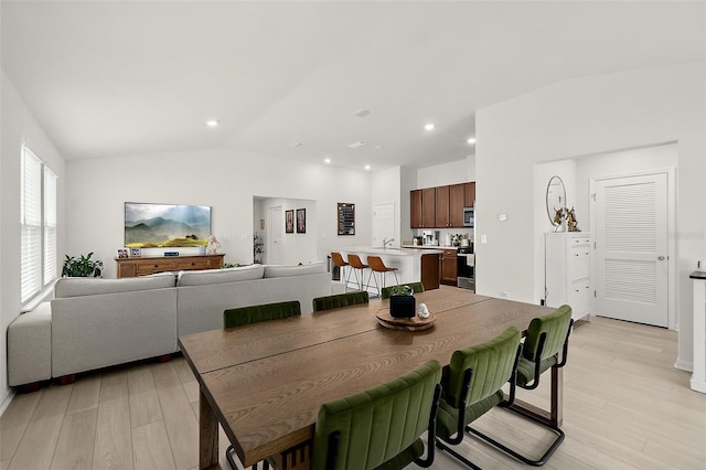 dining space featuring vaulted ceiling, light wood-type flooring, and recessed lighting