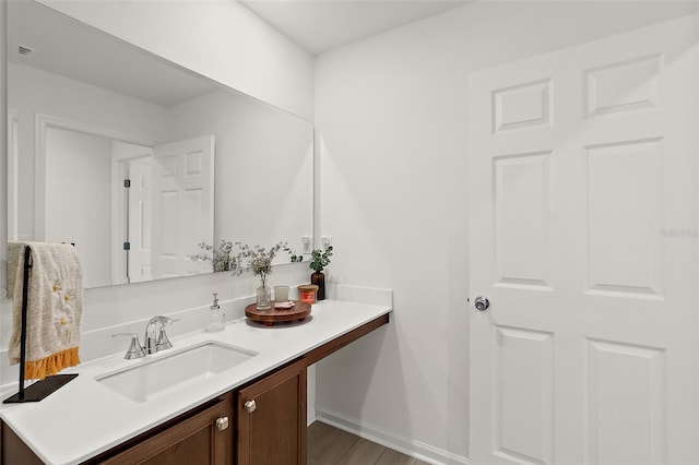 bathroom with baseboards, wood finished floors, and vanity