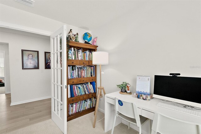 home office featuring light wood-style flooring, built in desk, visible vents, and baseboards