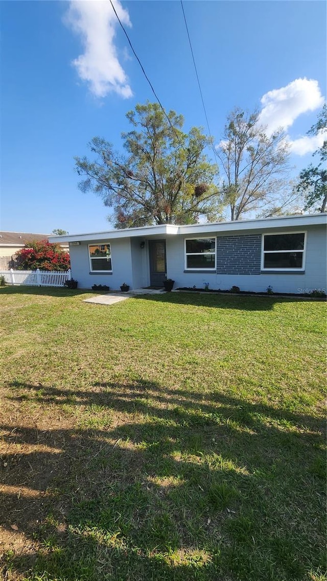 view of front of home featuring fence and a front lawn