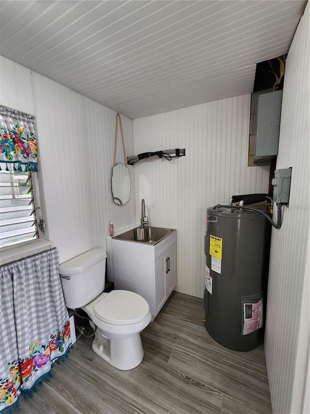 bathroom featuring toilet, a sink, water heater, and wood finished floors