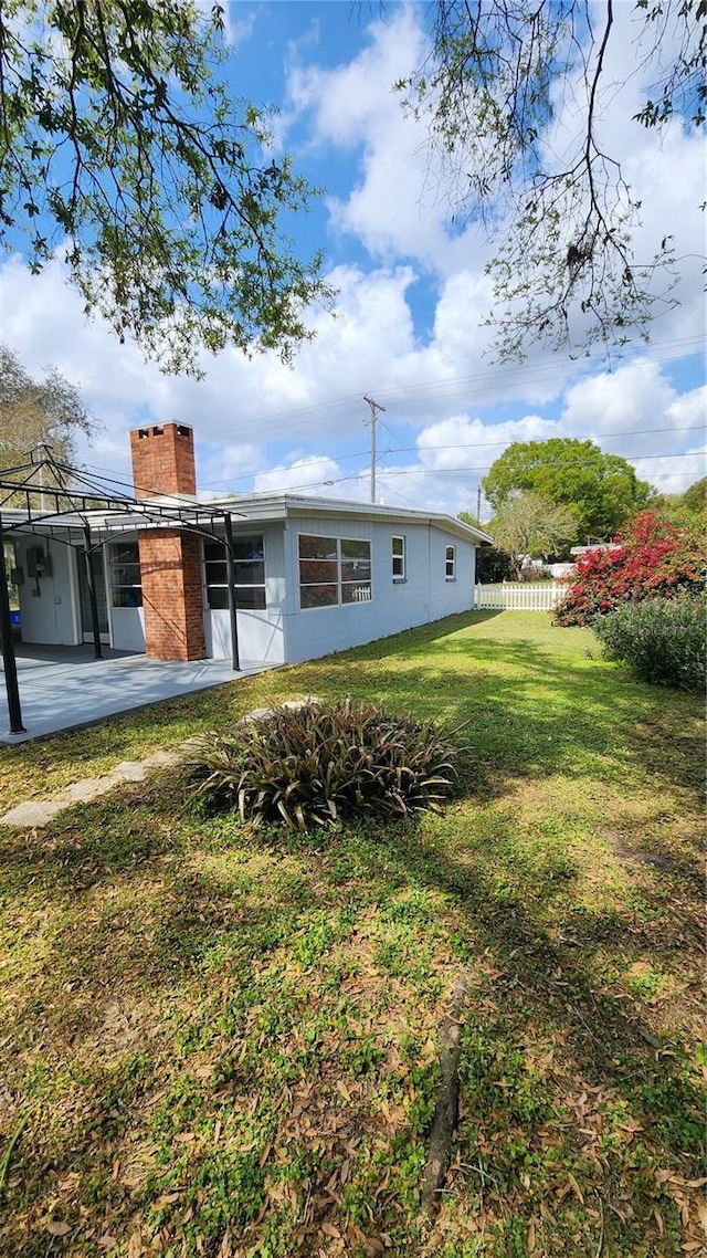 view of front facade with a front yard, a patio area, fence, and a chimney