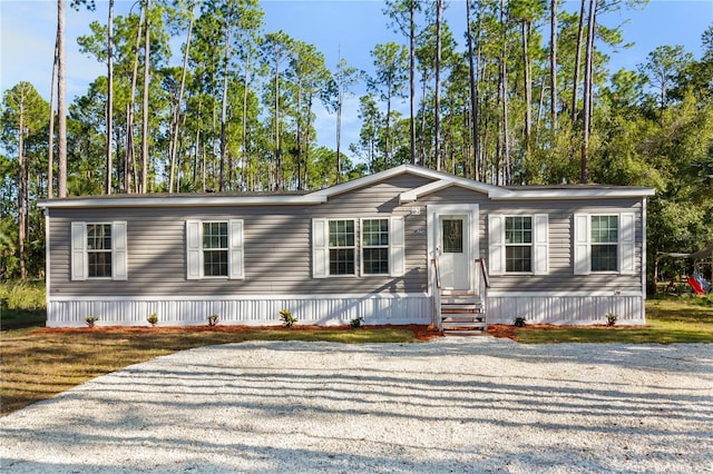 manufactured / mobile home with entry steps and gravel driveway