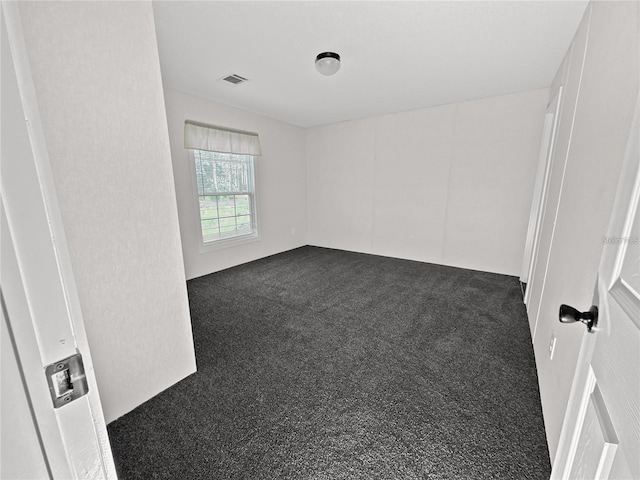 unfurnished room with dark colored carpet and visible vents