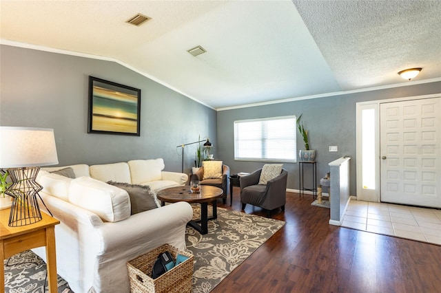 living area with visible vents, crown molding, lofted ceiling, and wood finished floors