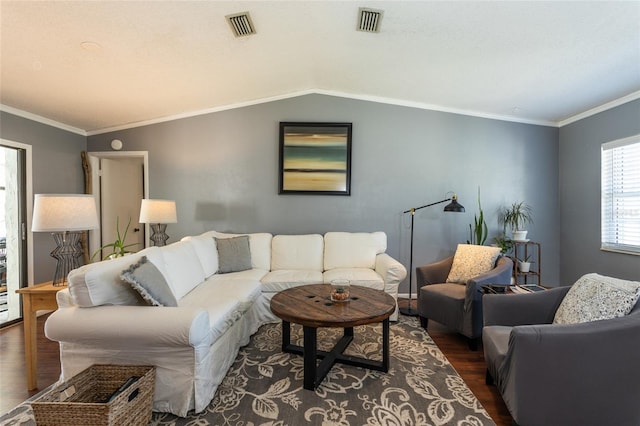 living room featuring dark wood finished floors, lofted ceiling, visible vents, and ornamental molding