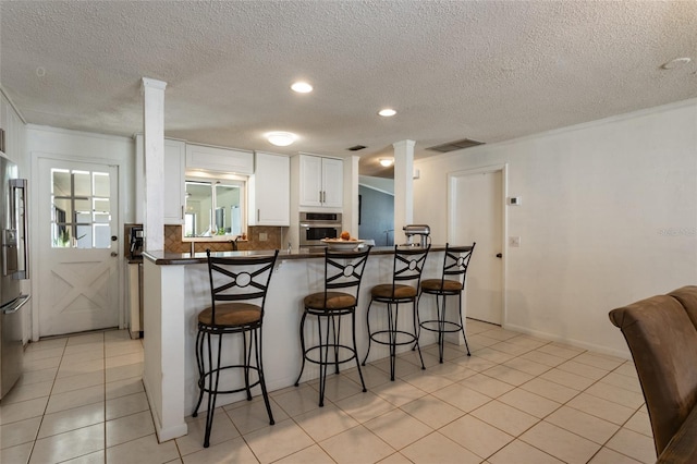 kitchen featuring dark countertops, white cabinets, stainless steel appliances, and a breakfast bar