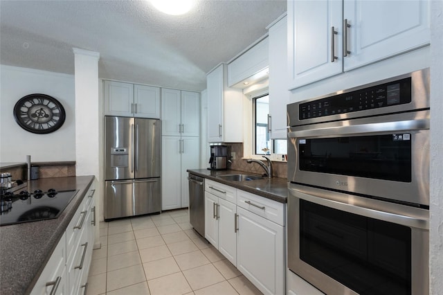 kitchen with dark countertops, backsplash, light tile patterned flooring, stainless steel appliances, and a sink