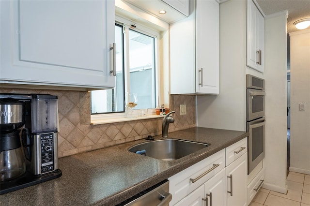 kitchen with light tile patterned floors, white cabinets, tasteful backsplash, and a sink