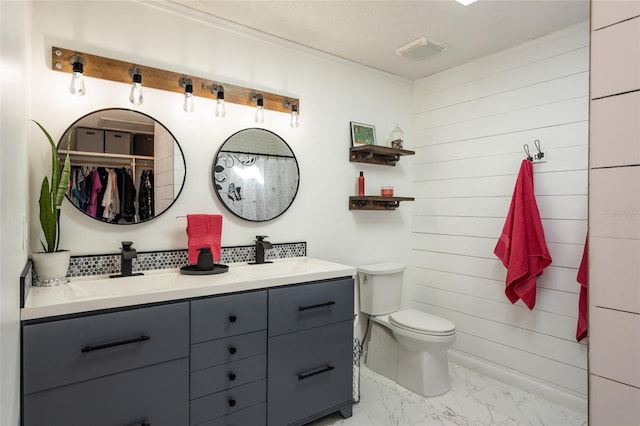 full bath with double vanity, toilet, marble finish floor, and a sink