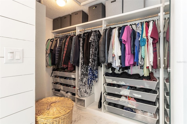 walk in closet featuring marble finish floor