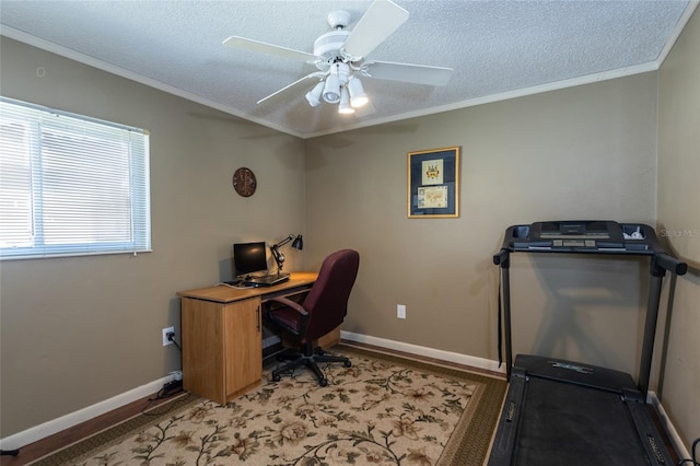 home office with a textured ceiling, a ceiling fan, baseboards, and ornamental molding