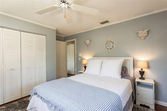 bedroom with wood finished floors, visible vents, a closet, a textured ceiling, and crown molding