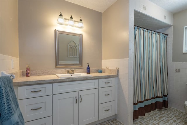 full bathroom with vanity, a shower with shower curtain, wainscoting, tile walls, and toilet