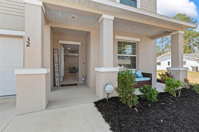 entrance to property featuring stucco siding, a porch, and an attached garage