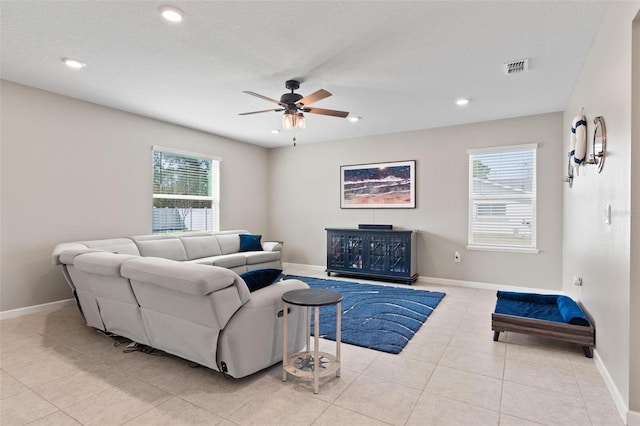 living area featuring light tile patterned floors, baseboards, visible vents, and a wealth of natural light