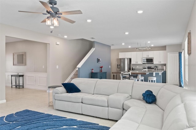 living area with light tile patterned floors, recessed lighting, ceiling fan, stairs, and a decorative wall