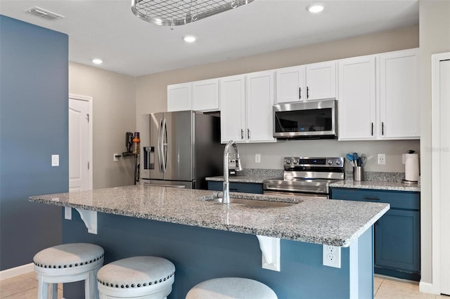 kitchen with visible vents, a sink, stainless steel appliances, white cabinets, and light tile patterned flooring