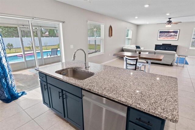 kitchen featuring a sink, open floor plan, a center island with sink, light stone counters, and stainless steel dishwasher