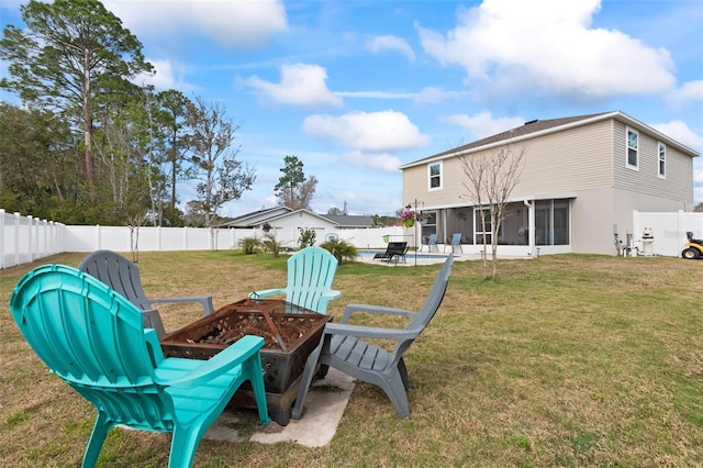 view of yard with a patio, an outdoor fire pit, a fenced backyard, and a sunroom