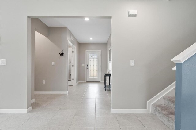 foyer with stairs, light tile patterned flooring, and baseboards