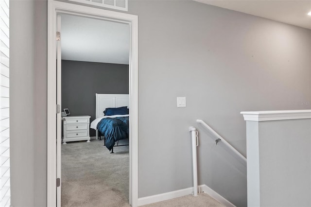 hallway featuring baseboards, an upstairs landing, carpet, and visible vents