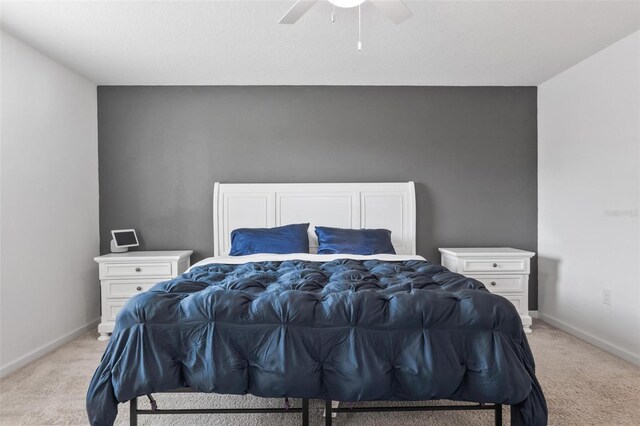 bedroom with light colored carpet, baseboards, and ceiling fan