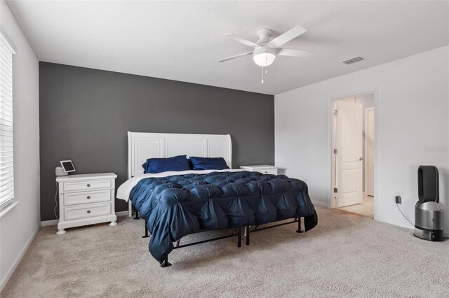 bedroom with visible vents, light carpet, baseboards, and a ceiling fan