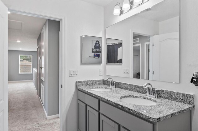 bathroom featuring double vanity, visible vents, baseboards, and a sink