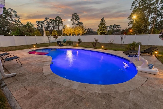 pool at dusk with a patio area, a fenced in pool, and a fenced backyard