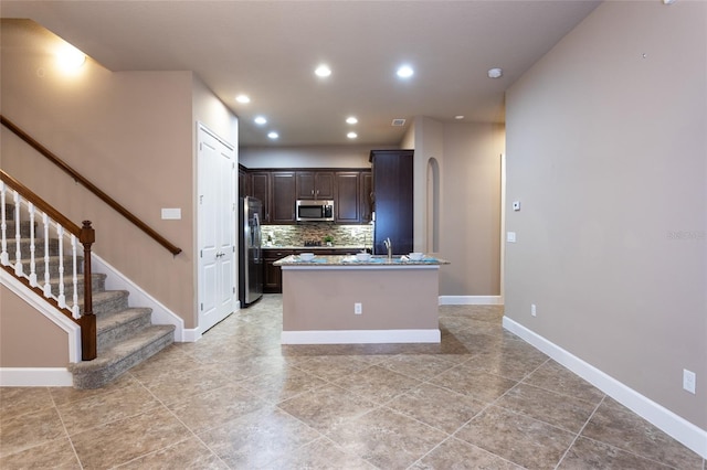 kitchen featuring dark brown cabinetry, recessed lighting, baseboards, appliances with stainless steel finishes, and tasteful backsplash