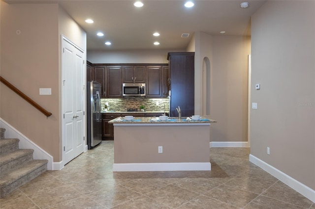 kitchen featuring tasteful backsplash, recessed lighting, appliances with stainless steel finishes, dark brown cabinetry, and a sink