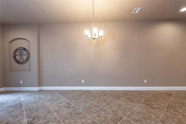 empty room featuring visible vents, a notable chandelier, and baseboards