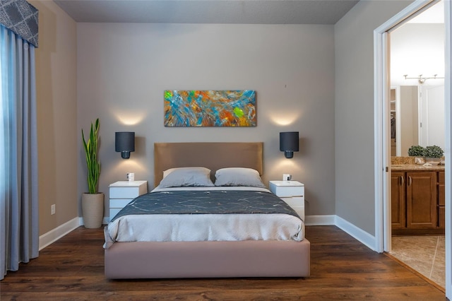 bedroom with baseboards, wood finished floors, and ensuite bathroom