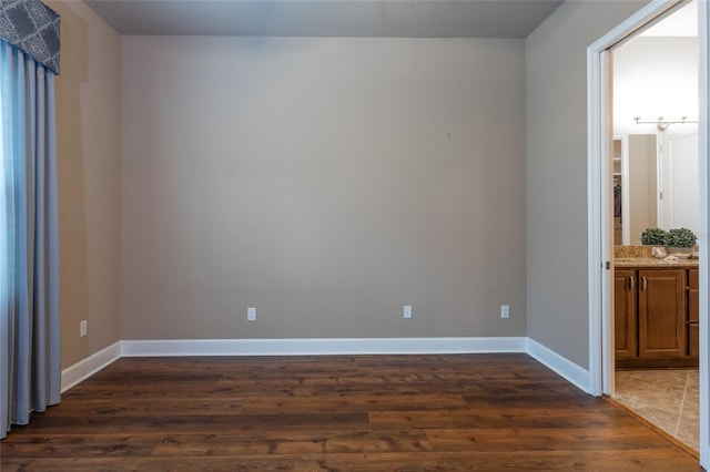 spare room with dark wood-style floors and baseboards