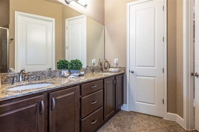 full bathroom featuring double vanity, a sink, a shower with door, and baseboards