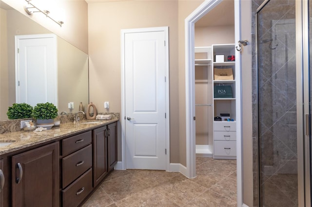 bathroom featuring a sink, double vanity, a spacious closet, and a shower stall