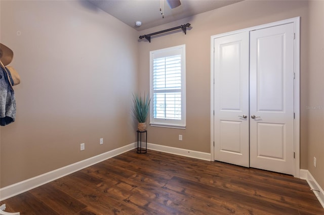 unfurnished bedroom with ceiling fan, a closet, baseboards, and dark wood-type flooring