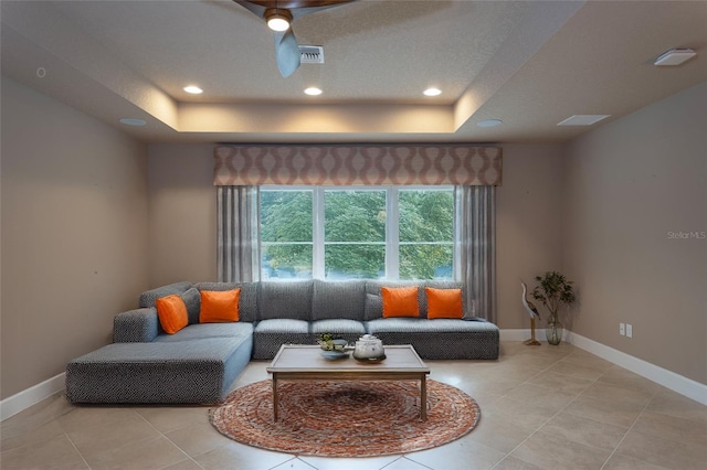 living area with a tray ceiling, recessed lighting, visible vents, and baseboards