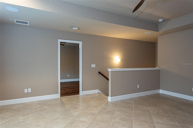 spare room featuring tile patterned flooring, visible vents, a textured ceiling, and baseboards