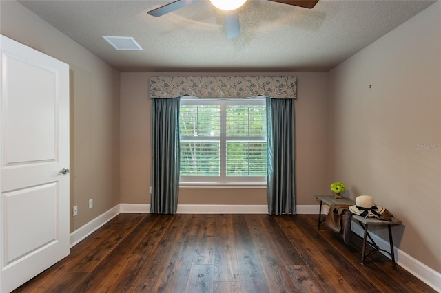 empty room featuring dark wood-style flooring, visible vents, ceiling fan, a textured ceiling, and baseboards