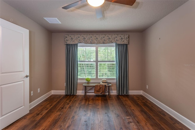 empty room featuring a textured ceiling, dark wood-style flooring, a ceiling fan, and baseboards