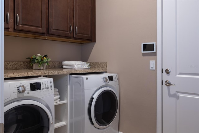 clothes washing area featuring washing machine and dryer and cabinet space